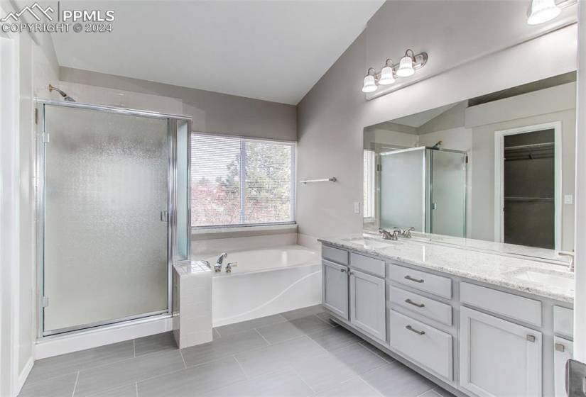 Bathroom with double sink, large vanity, shower with separate bathtub, and tile floors
