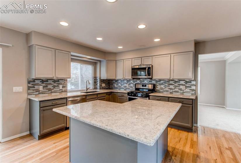 Kitchen featuring appliances with stainless steel finishes, light carpet, gray cabinets, and sink