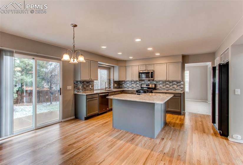 Kitchen with an inviting chandelier, stainless steel appliances, light wood-type flooring, and gray cabinetry