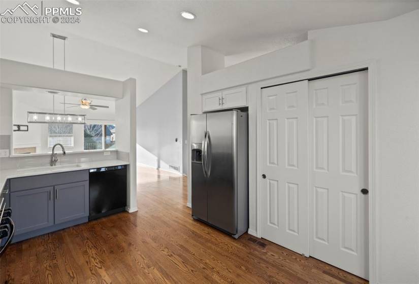 Kitchen featuring dark hardwood / wood-style floors, black dishwasher, sink, hanging light fixtures, and stainless steel fridge