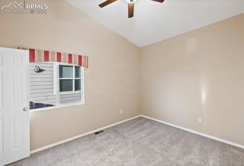 Spare room featuring vaulted ceiling, light colored carpet, and ceiling fan
