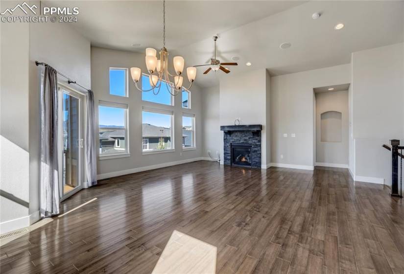 Great Room Features Gas Fireplace with Stacked Stone Surround + Mantel | Built-in Surround Sound | Open to Kitchen + Dining Area | 13' Vaulted Ceiling | Dual Directional Blinds