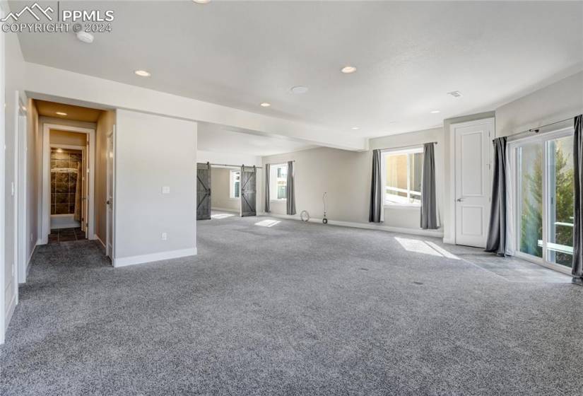 Spacious Basement Recreation Room | Hallway leading to Two Bedrooms, a Full Bath + Storage Closet