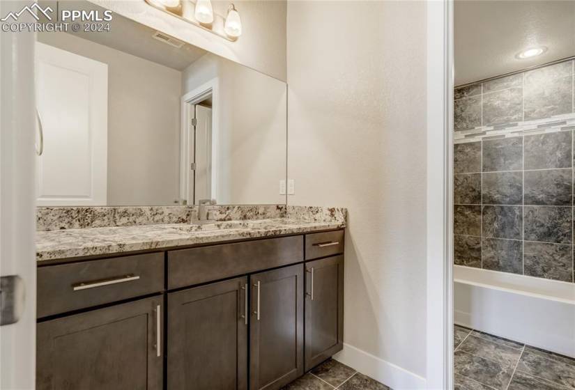 Basement Full Bathroom with Slab Granite Countertops + Backsplash + Tile Floor