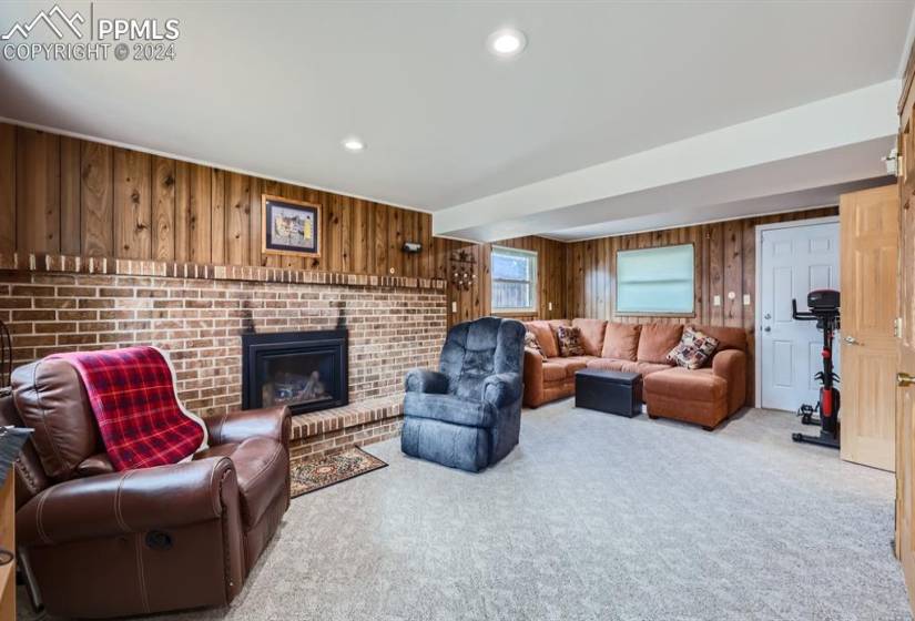 Family room with light colored carpet, wooden walls, and a fireplace