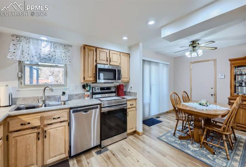 Kitchen featuring appliances with stainless steel finishes, light hardwood / wood-style flooring, sink, and ceiling fan