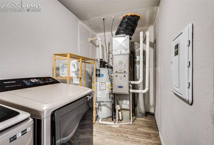 Laundry area featuring hardwood / wood-style flooring, washing machine and clothes dryer, and water heater