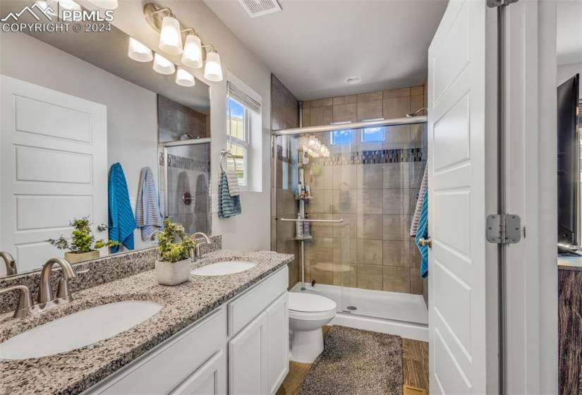 Bathroom featuring an enclosed shower, toilet, hardwood / wood-style flooring, and dual bowl vanity
