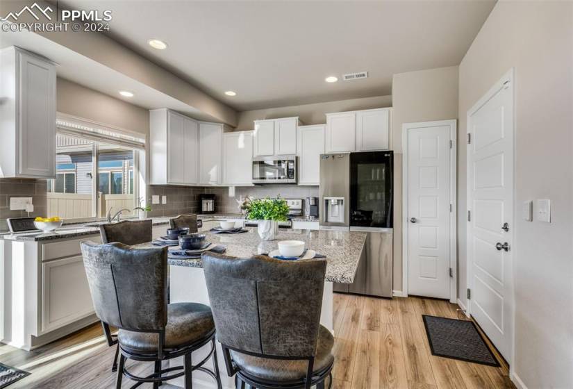 Kitchen featuring a center island, white cabinets, backsplash, appliances with stainless steel finishes, and light hardwood / wood-style flooring