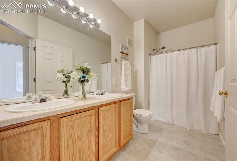 Large bathroom has new vertical tile flooring, new toilet and tons of counter space.