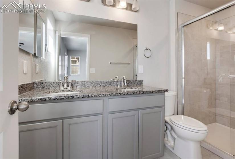 The master bath offers a granite double vanity and glass enclosed tiled shower.