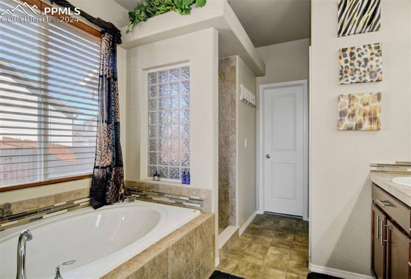 Bathroom featuring vanity, a relaxing tiled bath, and tile floors