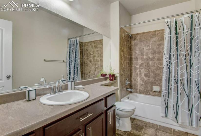 Full bathroom featuring toilet, vanity with extensive cabinet space, tile flooring, and shower / tub combo with curtain