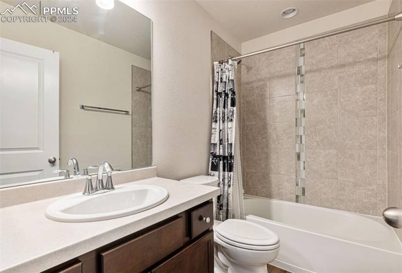 Full bathroom with shower / bathtub combination with curtain, toilet, and vanity