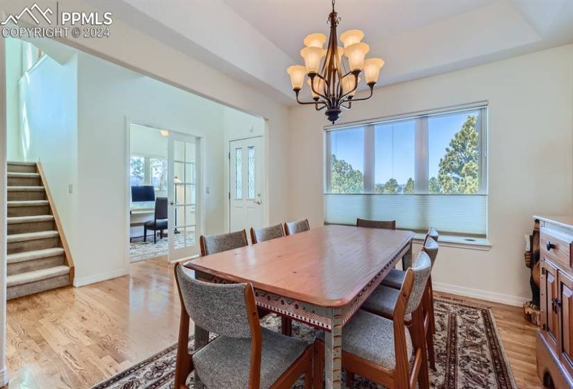 Dining area with an inviting chandelier, a tray ceiling & hardwood flooring.