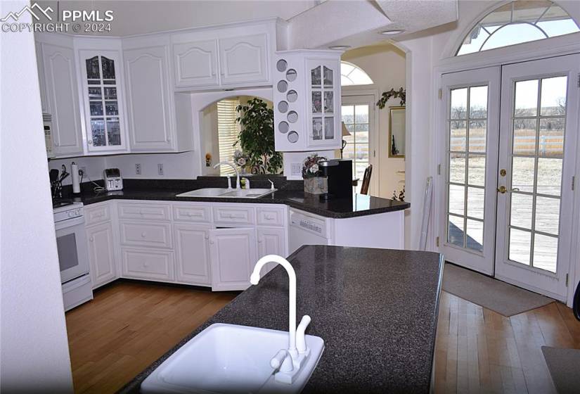 Kitchen with white appliances, french doors, sink, hardwood / wood-style flooring, and white cabinetry