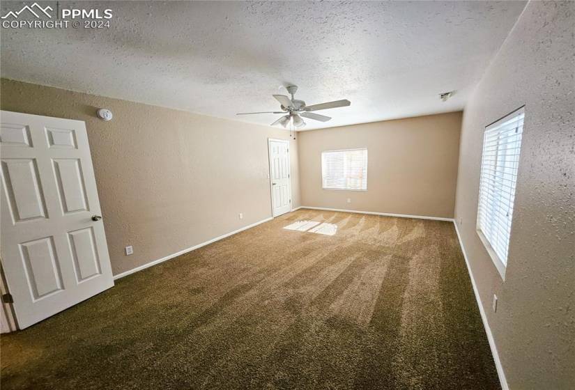 Spare room with a textured ceiling, dark colored carpet, and ceiling fan