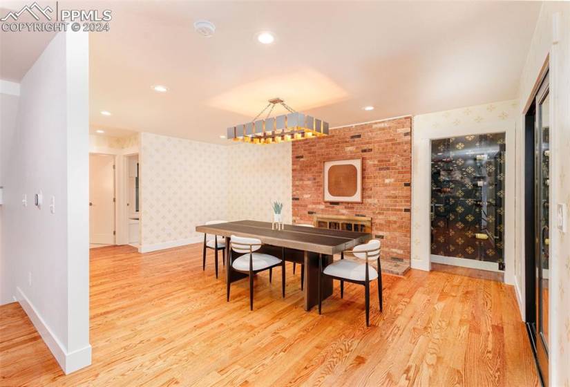 Dining room featuring brick wall, wine pantry, light hardwood / wood-style flooring, and an inviting chandelier
