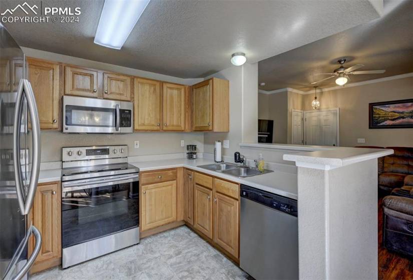 Kitchen featuring light tile flooring, sink, kitchen peninsula, appliances with stainless steel finishes, and ceiling fan