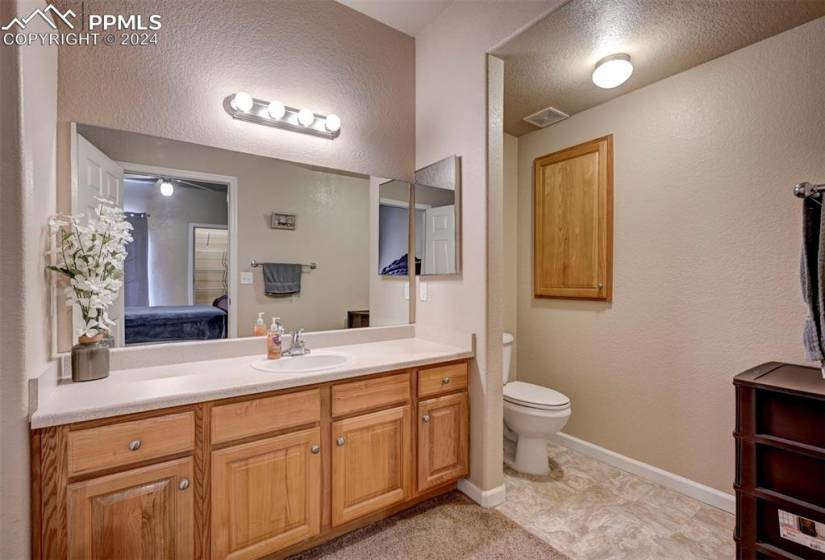Bathroom featuring vanity, toilet, a textured ceiling, and tile floors