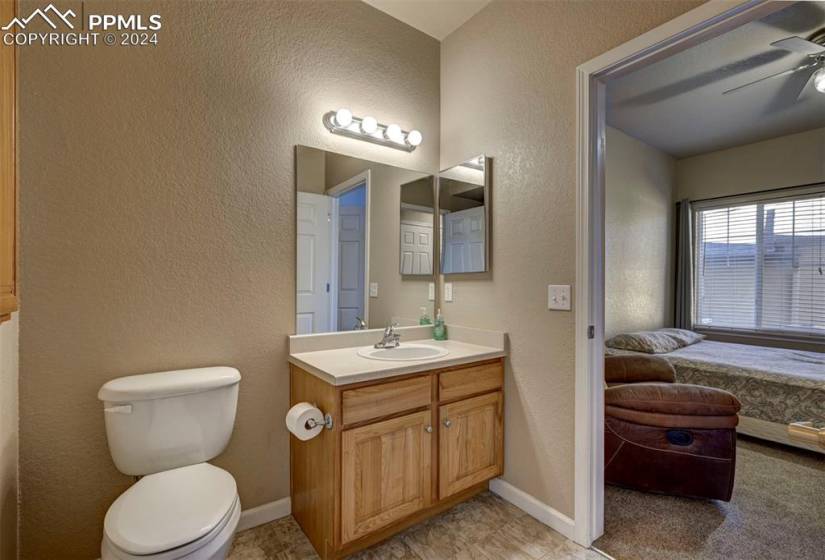 Bathroom with toilet, tile flooring, ceiling fan, and large vanity