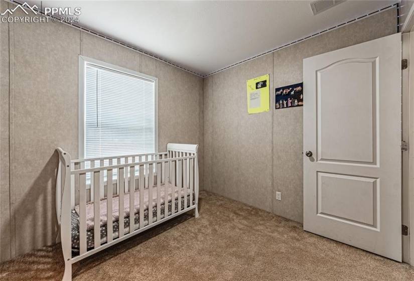 Bedroom with light carpet and a crib