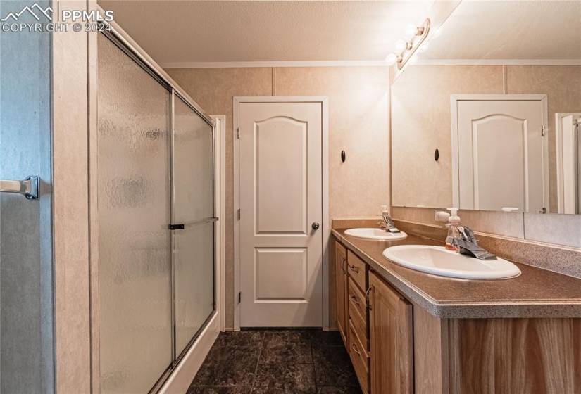 Bathroom with an enclosed shower, dual bowl vanity, tile floors, and crown molding