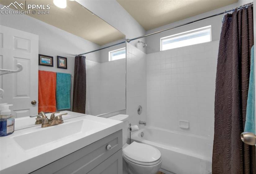 Full bathroom with shower / bathtub combination with curtain, toilet, and vanity
