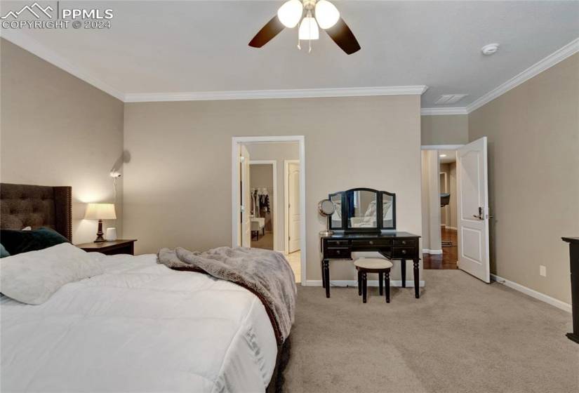 Bedroom with ornamental molding, light carpet, and ceiling fan