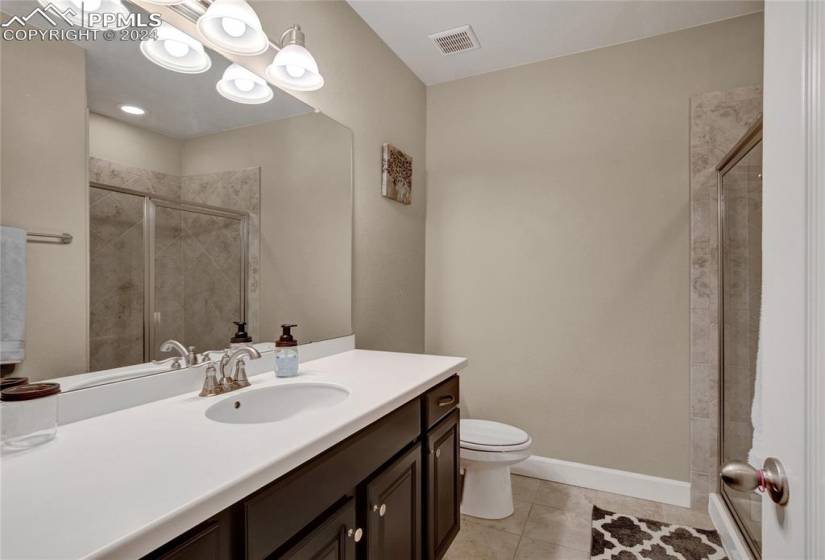 Bathroom with vanity, tile flooring, a shower with shower door, and toilet