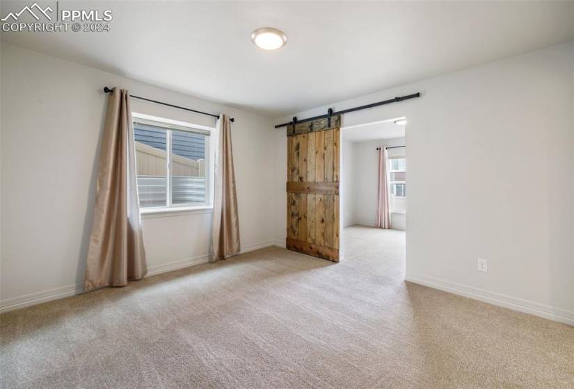 Bedroom or flex space with barn door and light carpet