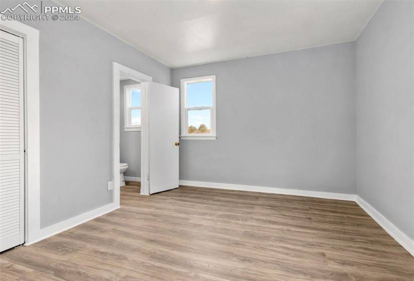 Unfurnished bedroom with a closet, light hardwood / wood-style floors, and ensuite bath