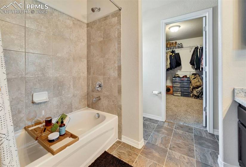 Bathroom with tile walls, tile floors, shower / tub combo, and vanity