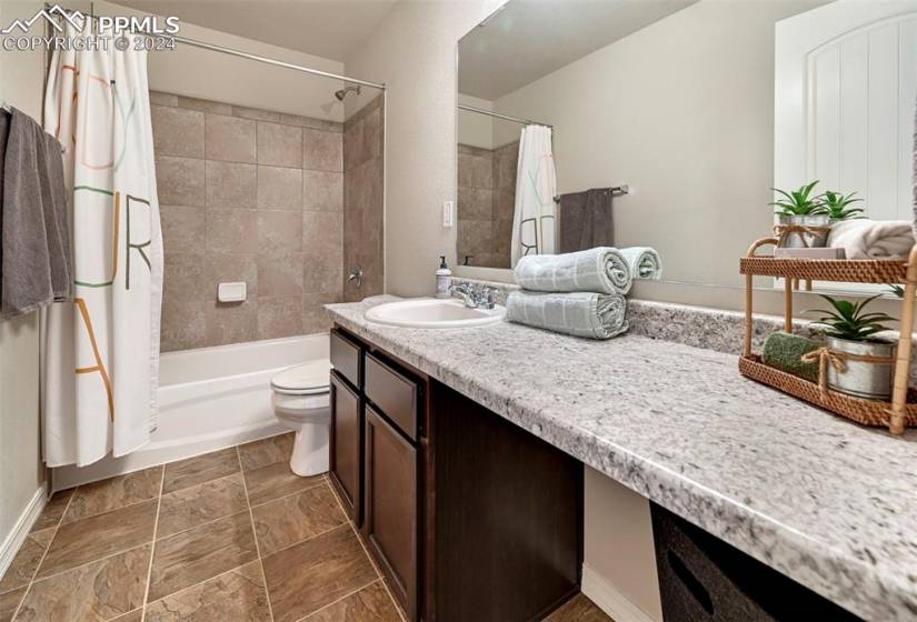 Full bathroom with vanity, toilet, tile flooring, and shower / tub combo