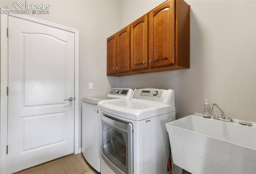 Clothes washing area featuring sink, cabinets, and washer and dryer