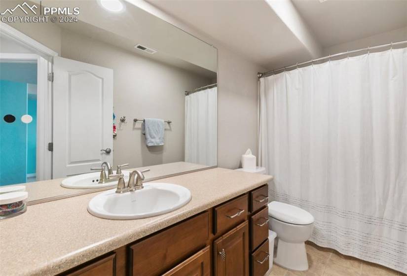 Bathroom featuring tile floors, toilet, and large vanity