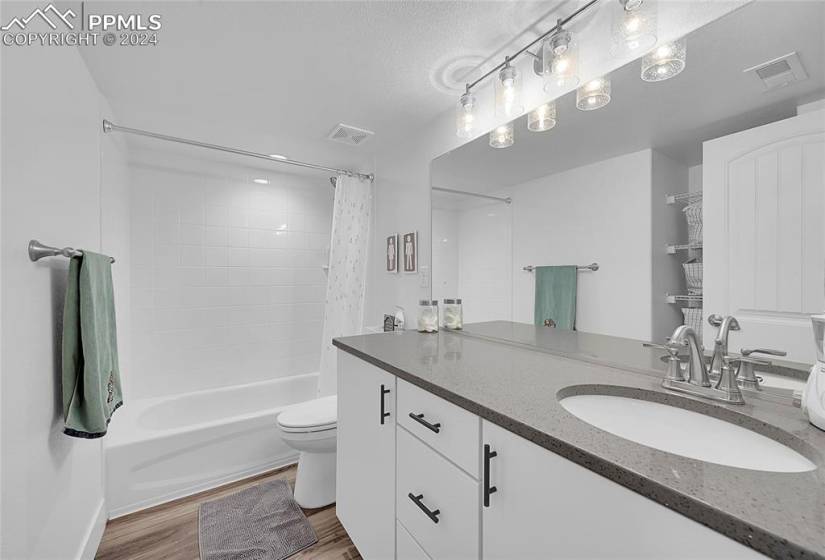 Basement full bathroom with quartz CT's vanity, toilet, LVP flooring, and shower / bath combo