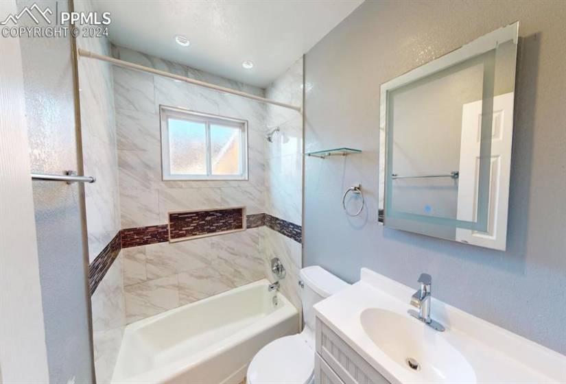 Full bathroom featuring tiled shower / bath combo, toilet, and vanity