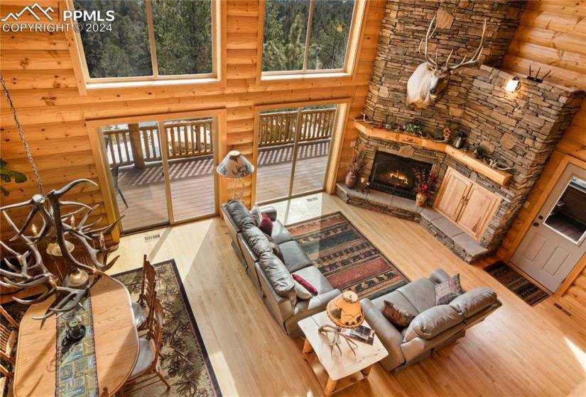Living room featuring rustic walls, a stacked stone fireplace, and Hickory hardwood floors