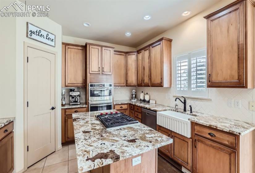 Kitchen featuring appliances with stainless steel finishes, a center island, light stone countertops, and sink