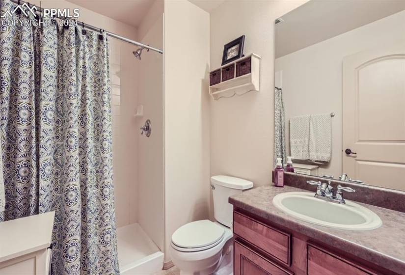 Bathroom featuring large vanity, toilet, and a shower with curtain