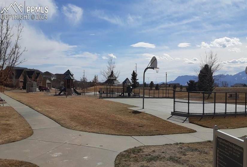 Surrounding community with a playground, a mountain view, and basketball court