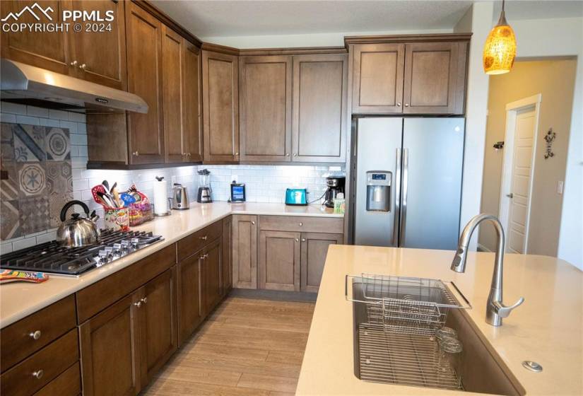 Kitchen featuring tasteful backsplash, sink, appliances with stainless steel finishes, decorative light fixtures, and light hardwood / wood-style floors