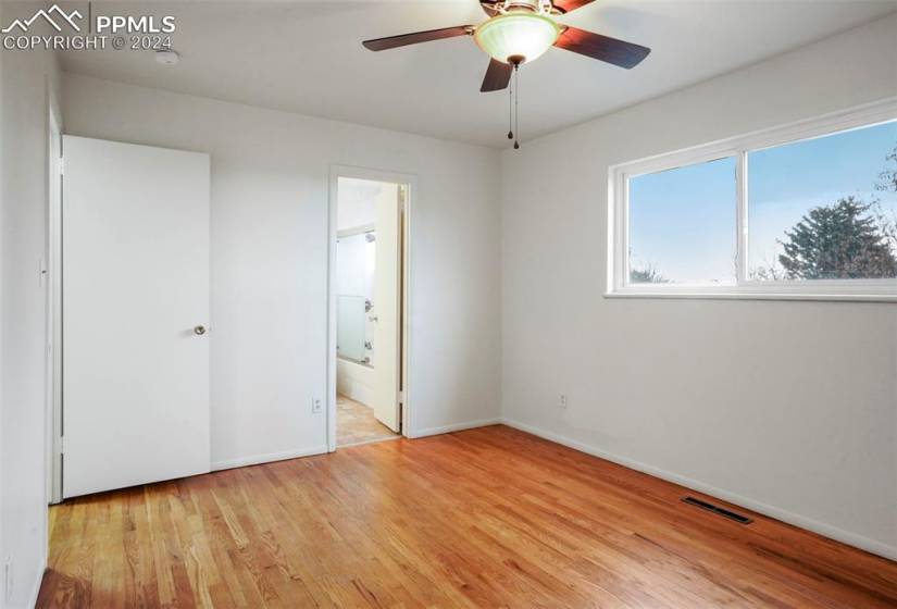 Unfurnished bedroom with ensuite bathroom, a closet, light hardwood / wood-style floors, and ceiling fan