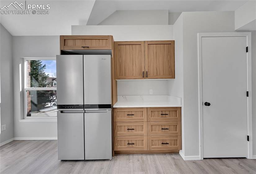Kitchen with lofted ceiling, light hardwood / wood-style flooring, and stainless steel refrigerator
