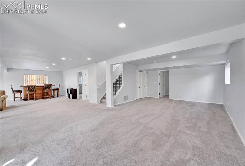 Basement with indoor bar and light colored carpet