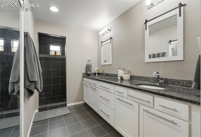 Master-bathroom featuring a tile shower, double vanity, and tile floors