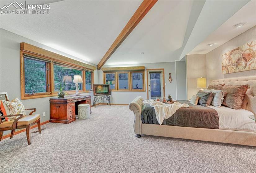 Bedroom featuring vaulted ceiling with beams and light colored carpet