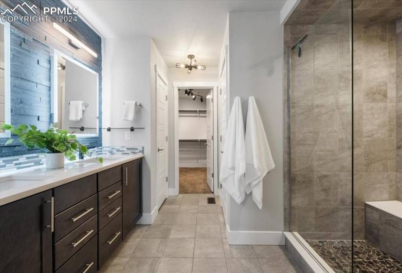 Bathroom featuring a shower with shower door, tile floors, and double sink vanity