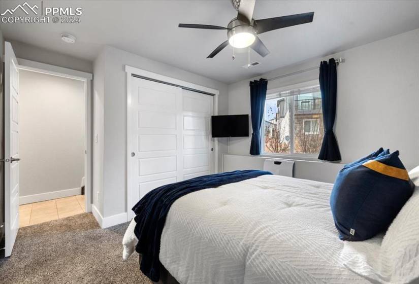 Bedroom featuring light carpet, ceiling fan, and a closet